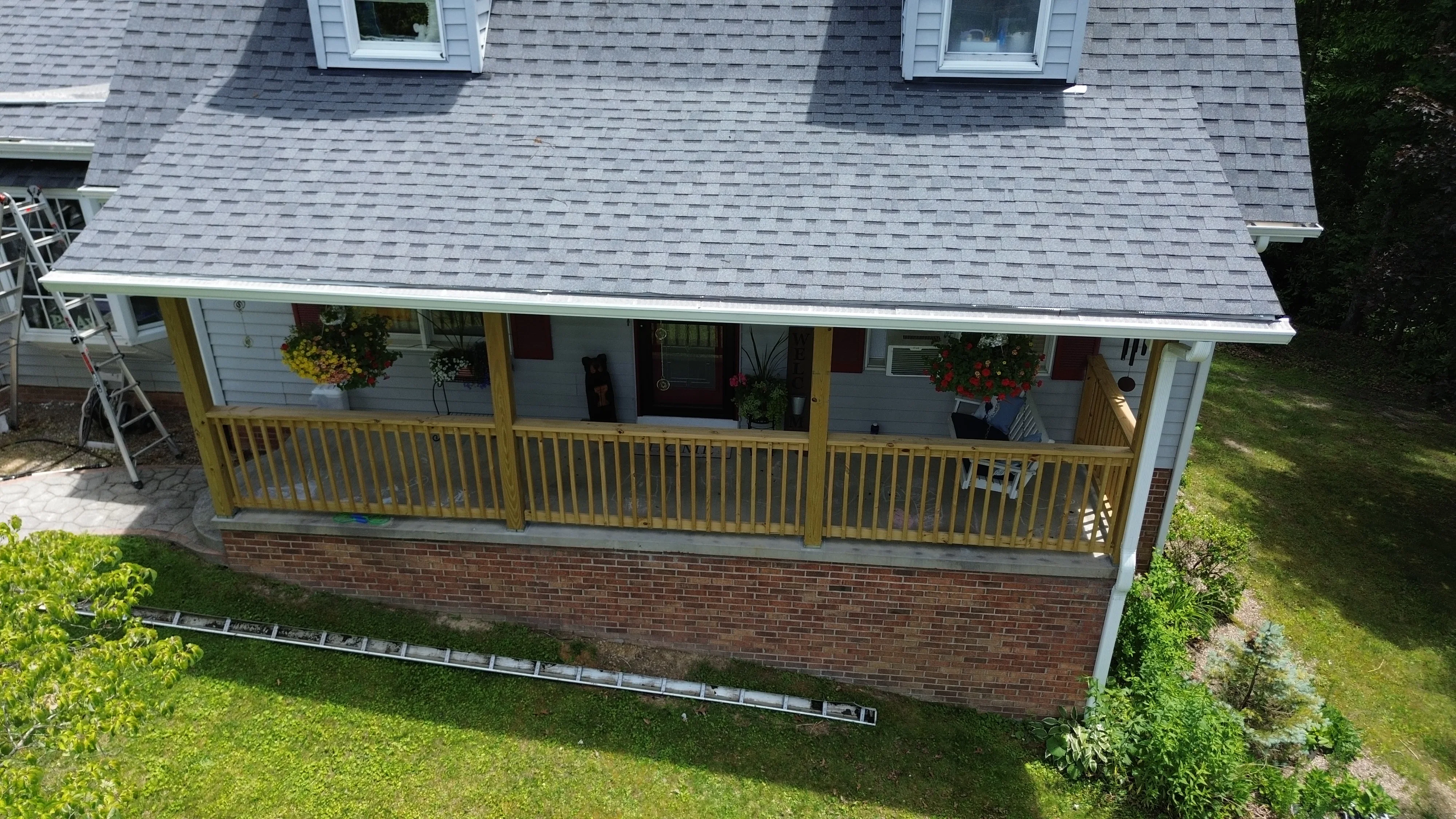 Seamless gutter installation with white trim on residential home with brick foundation and yellow porch railings