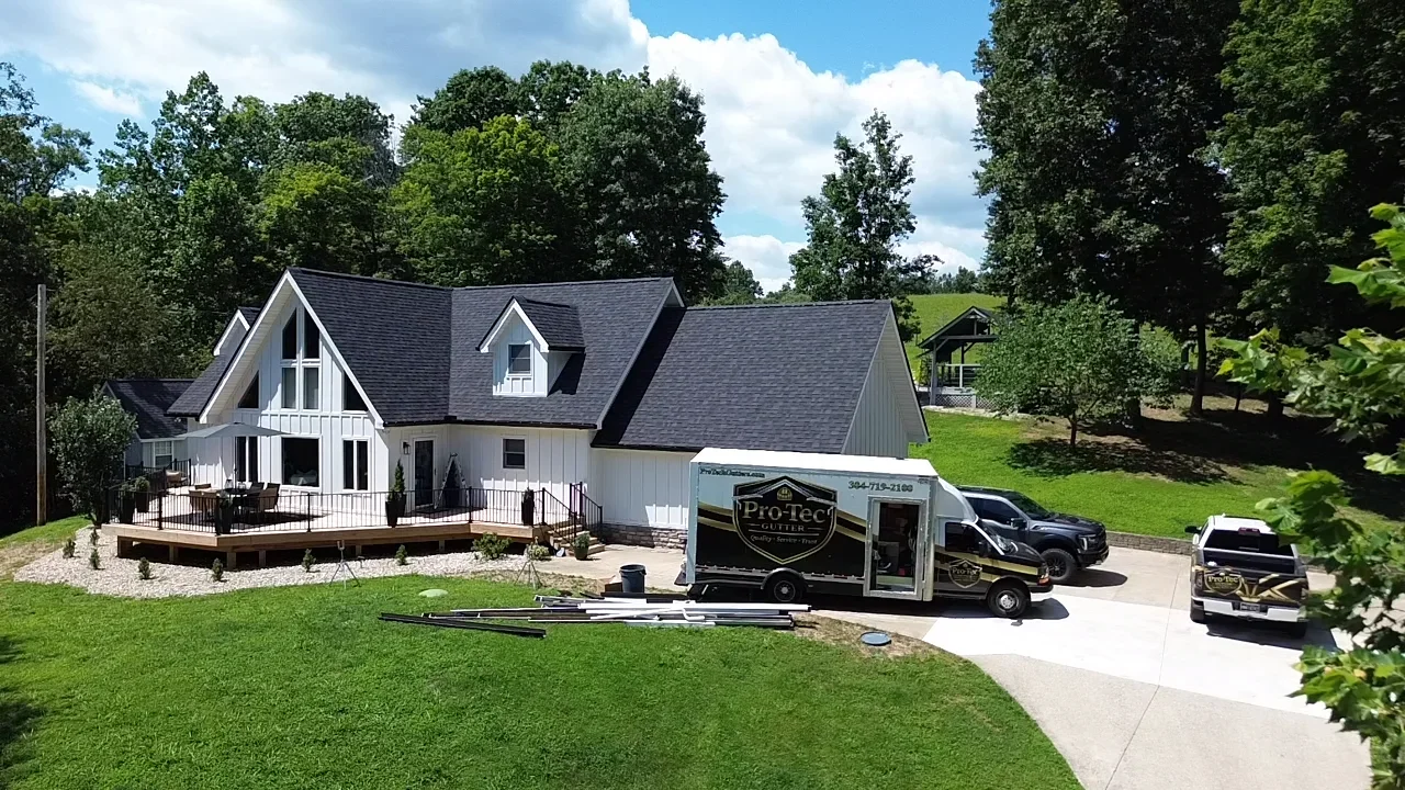 White farmhouse with dark gray roof and installed gutters with protection system
