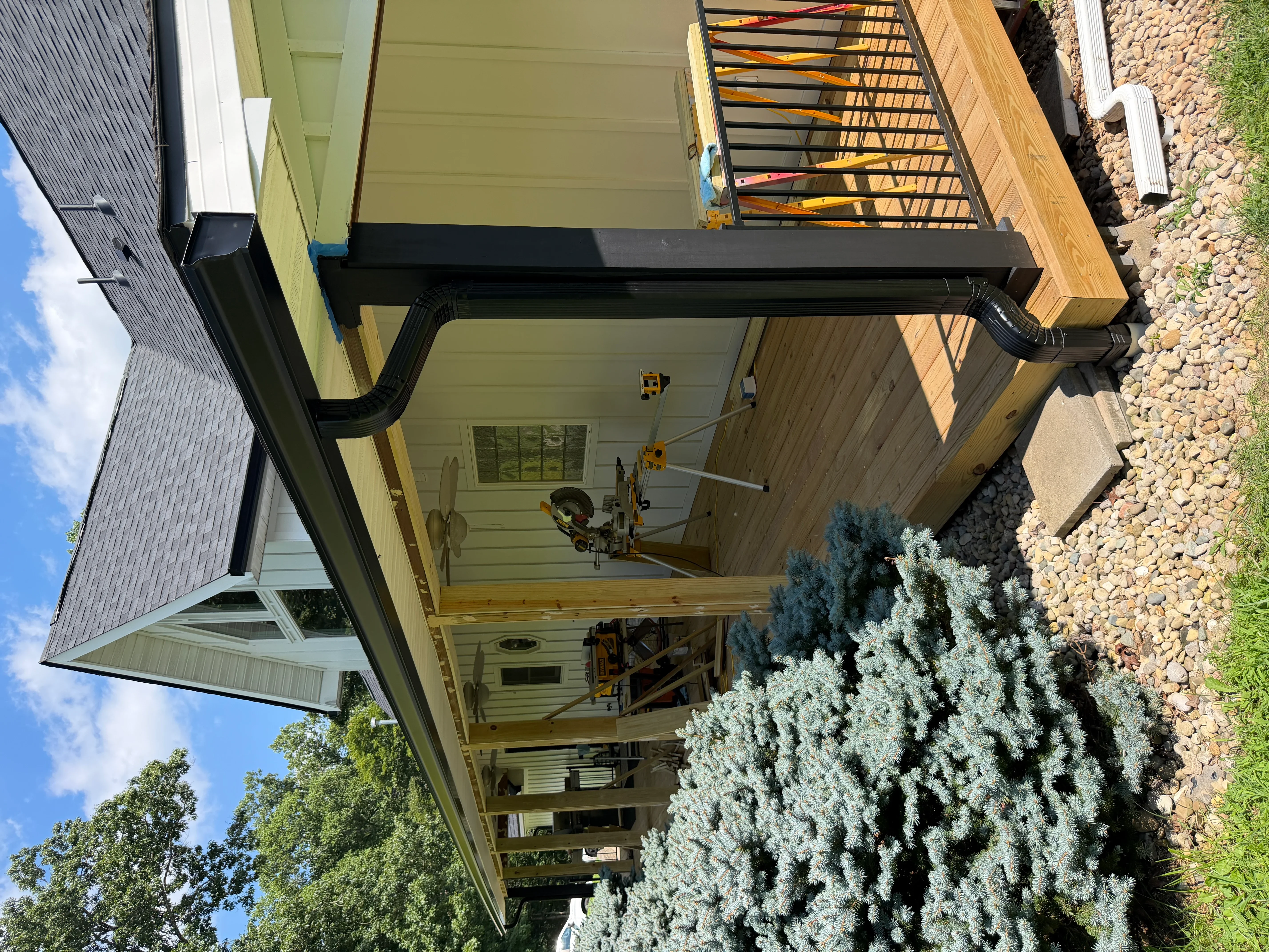 Black seamless gutter system with downspout installed on residential home exterior