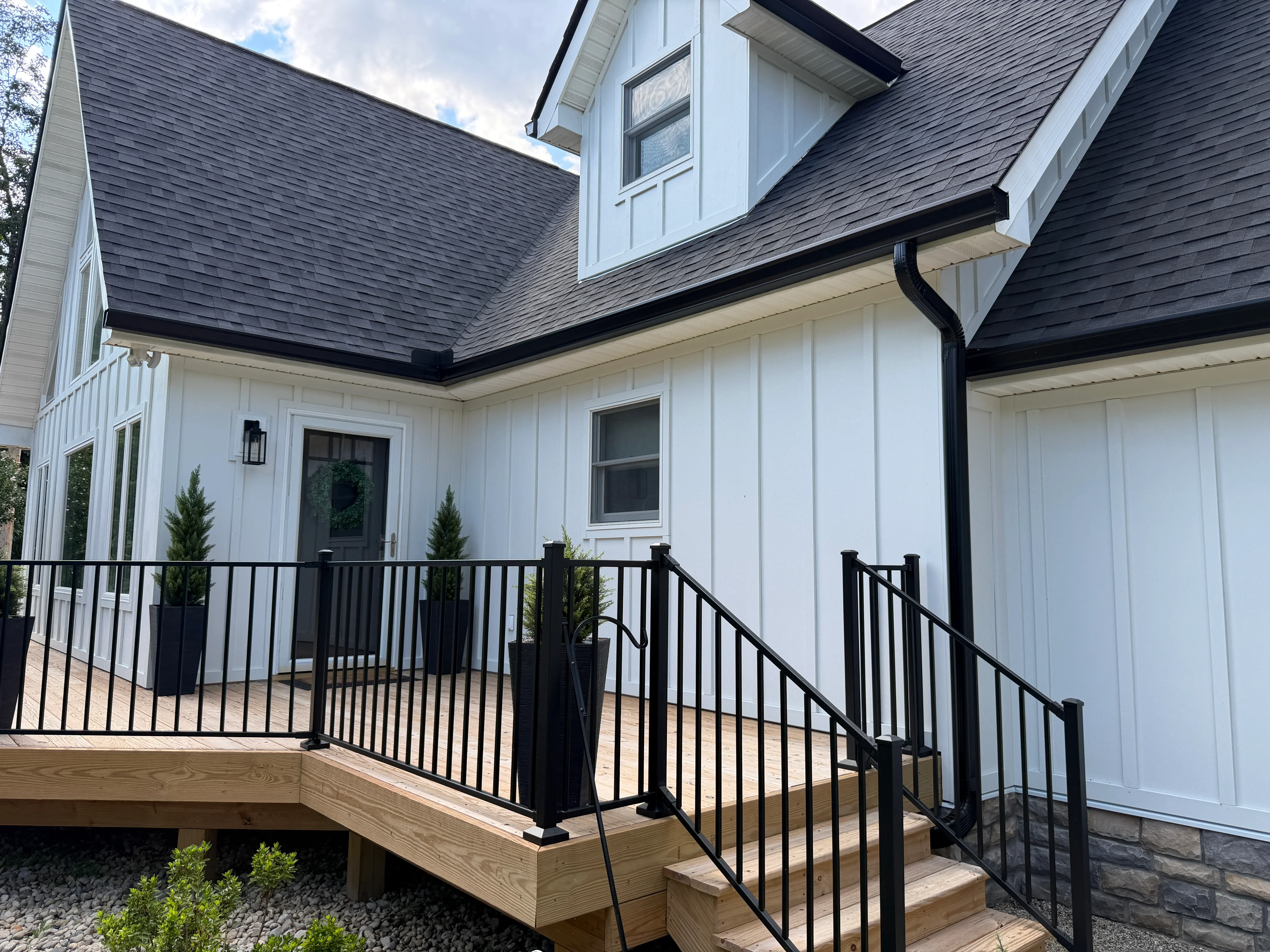 Black aluminum gutters and fascia on white farmhouse with dark roof shingles