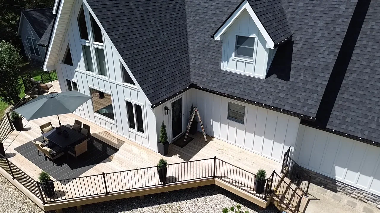 Black seamless gutters installed on multi-level home with white fascia and metal railings