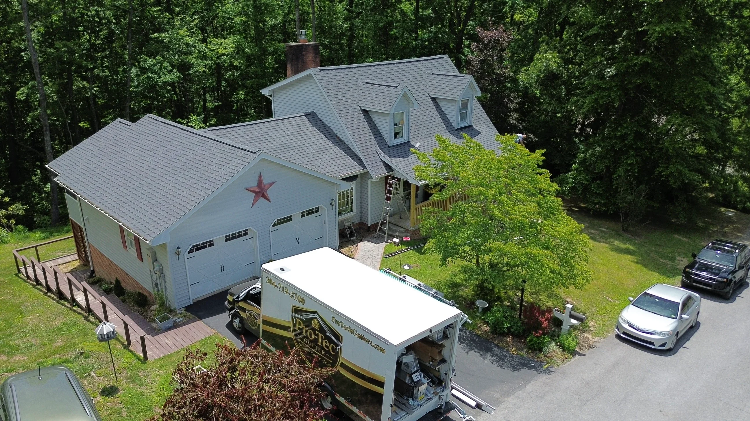 Two-story home with new gray seamless gutters installed across multiple roof sections and dormers