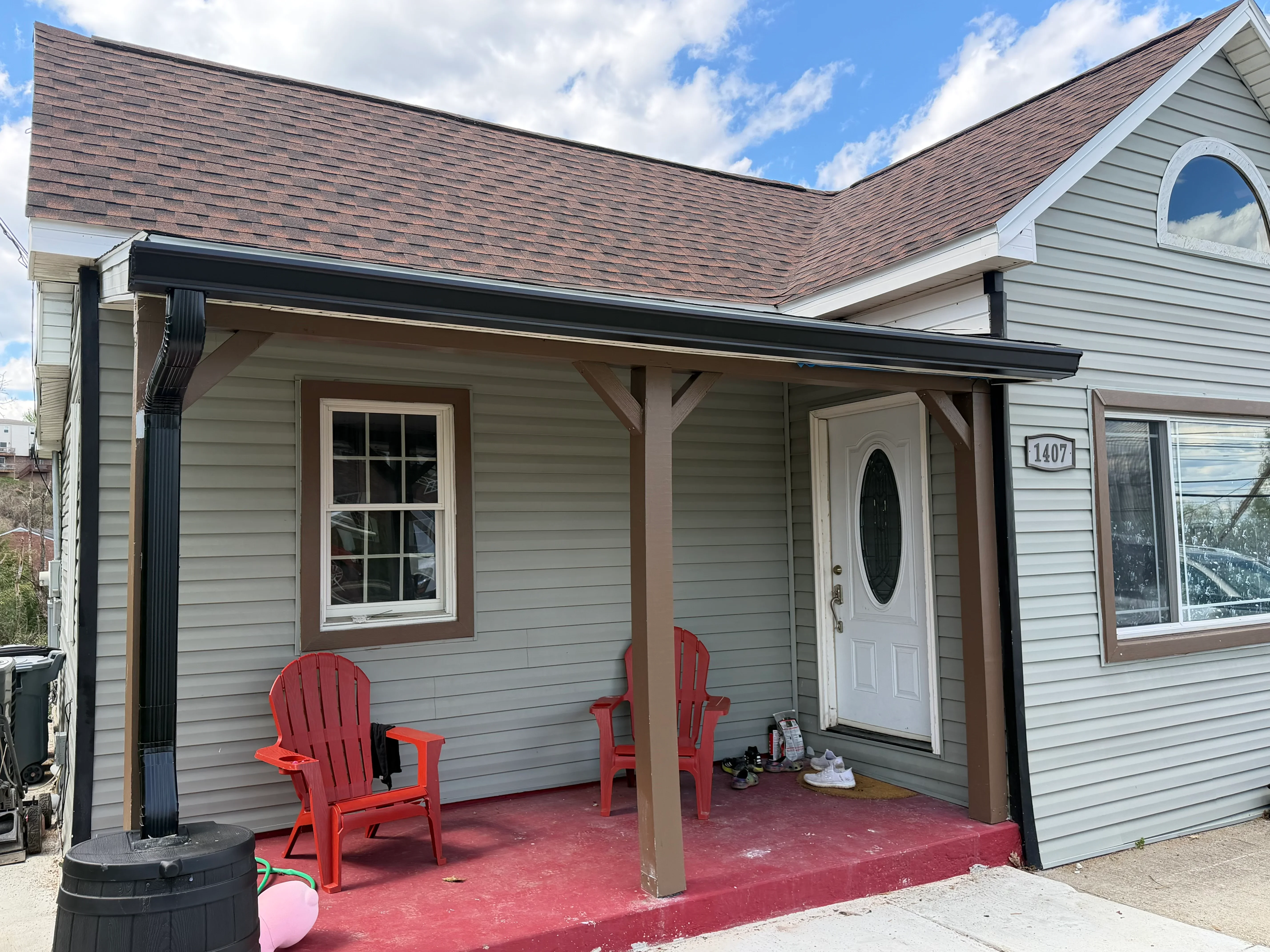 Black aluminum gutter and downspout on front porch with wood beam supports