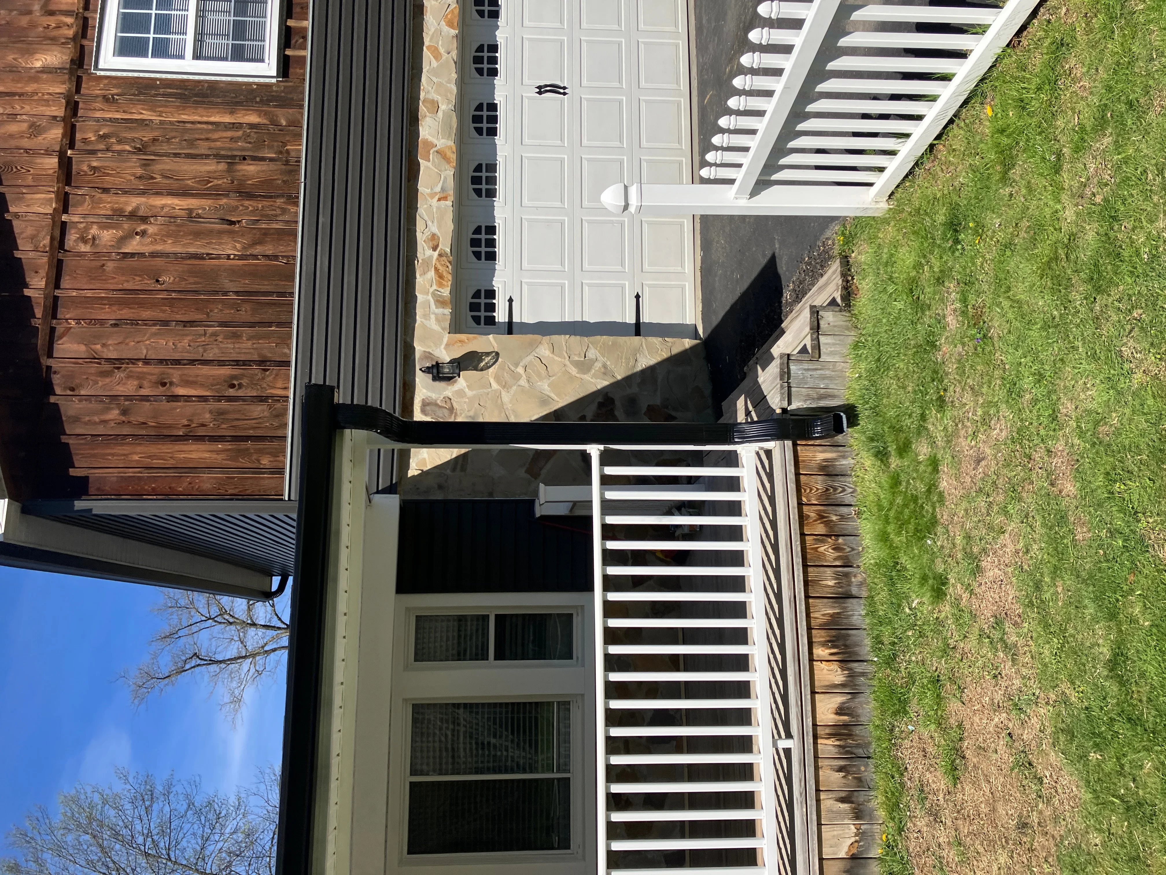 White aluminum gutters with downspouts installed on residential home with stone and wood siding