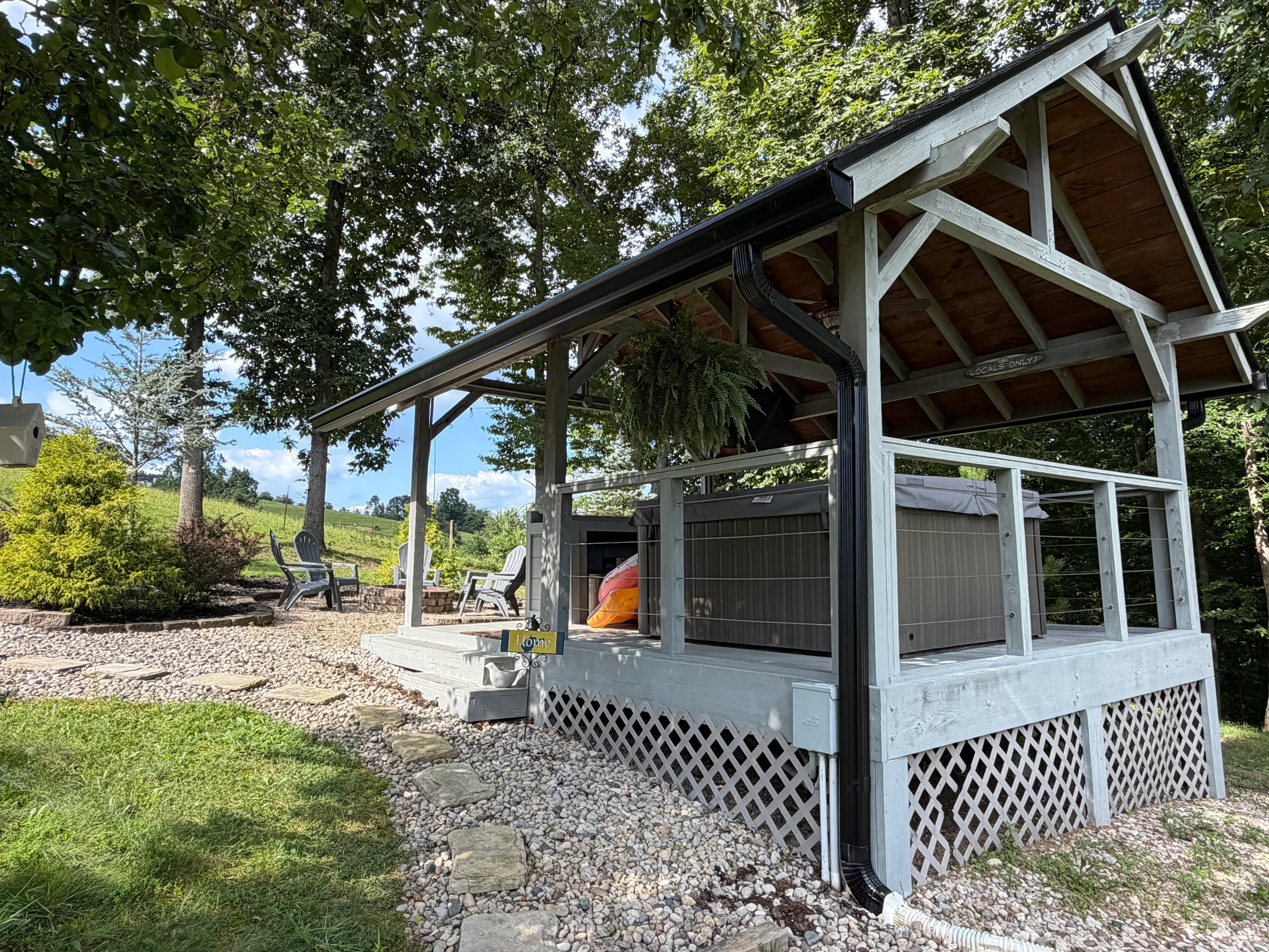 Screened pavilion with integrated gutter system, black downspouts, and lattice skirting on gravel base