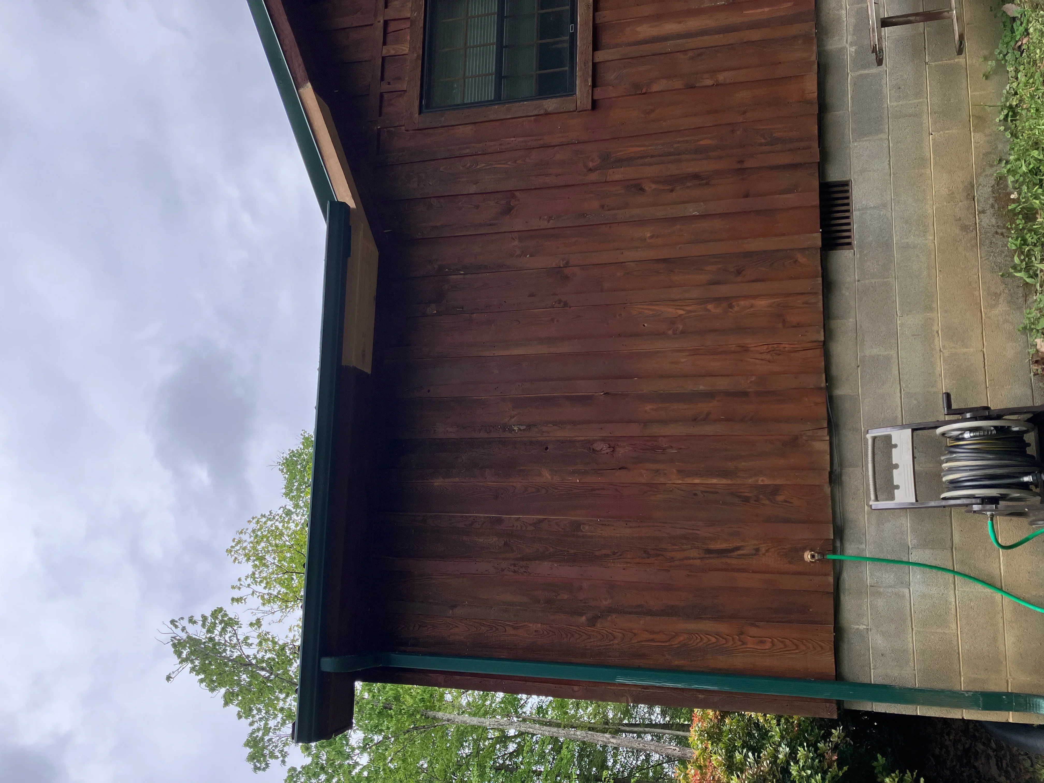 Green seamless gutter installed on wood-sided house with proper fascia attachment