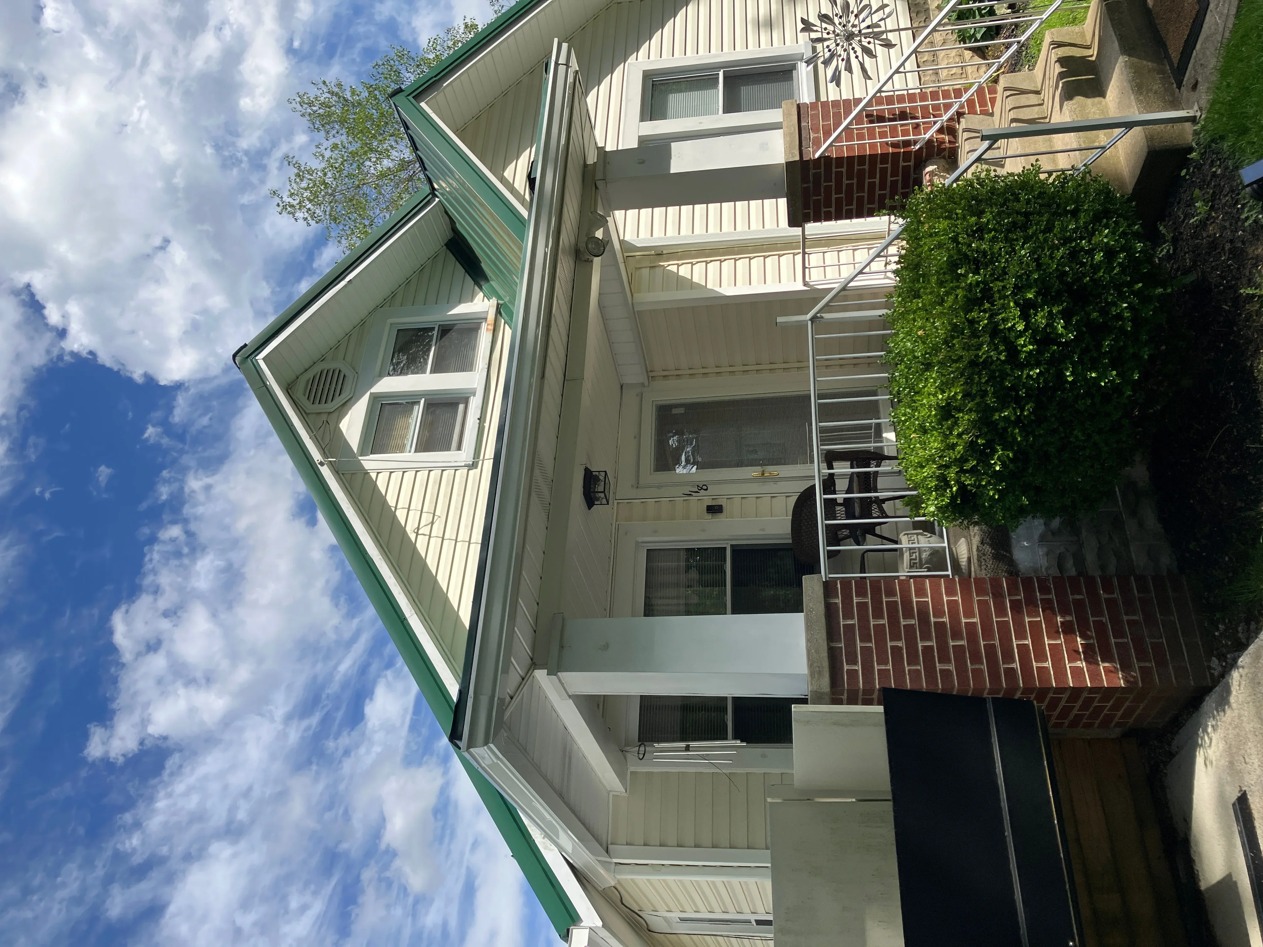 Three-story house with new metal gutters, green trim, and white fascia installation